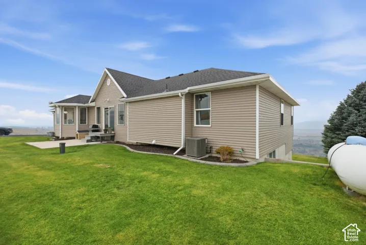 Rear exterior featuring tan horizontal siding, a gabled roofline, and a concrete patio