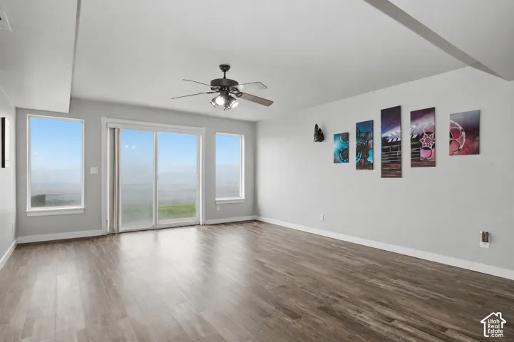 Spacious room with wood-finish flooring, light grey walls, and white trim