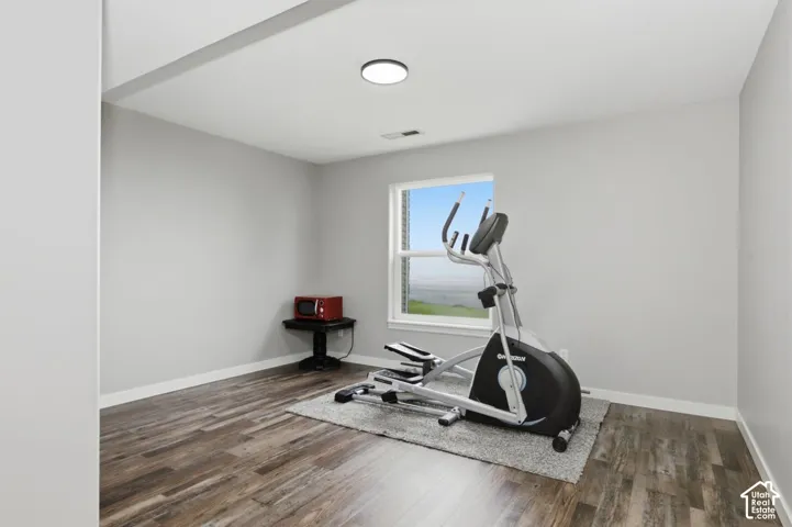 Versatile room featuring wood-finish flooring, light gray wall paint, and a modern flush-mount ceiling light