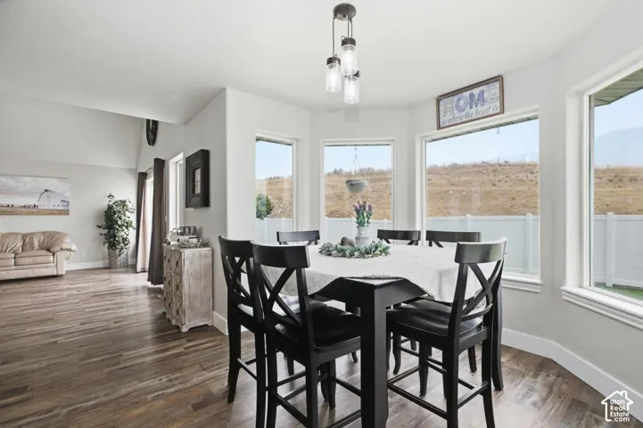 Naturally lit dining area featuring a bay window, wood-finish flooring, and a contemporary multi-light pendant fixture