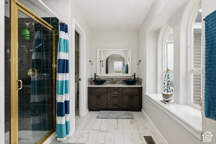 Bathroom featuring a dual vanity with vessel sinks, dark wood-finish cabinetry, and a stone-tiled backsplash