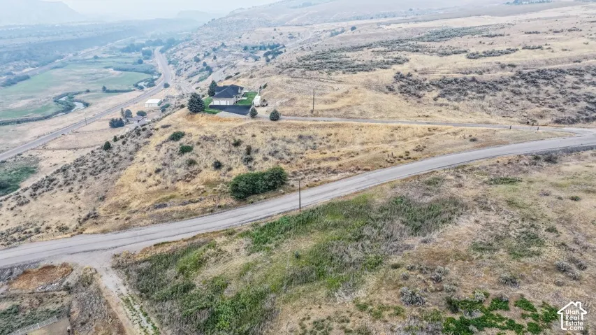 Expansive hillside property featuring a residential structure, paved driveway, and surrounding natural landscape