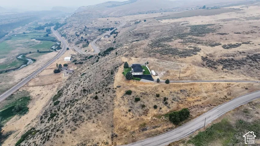 Expansive property featuring a contemporary residence, paved drive, and surrounding natural landscape