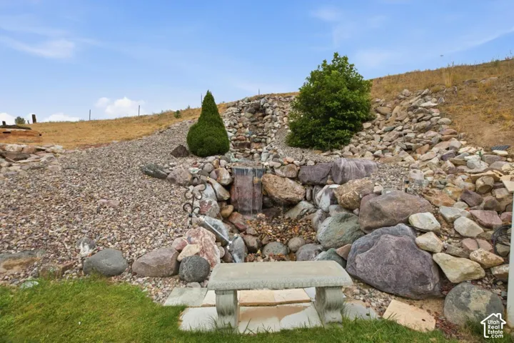 Stone water feature with a waterfall, surrounded by various rock sizes and landscaping