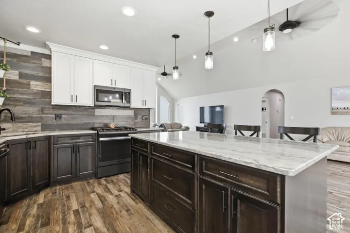 Kitchen featuring a spacious island with a light-toned countertop, dark wood-finish cabinetry, and contemporary pendant lighting