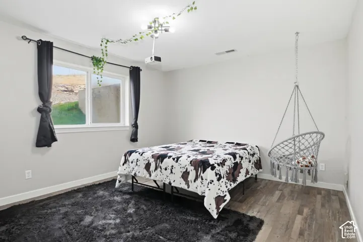 Room featuring wood-finish flooring, light gray walls, white baseboards, and a white window frame