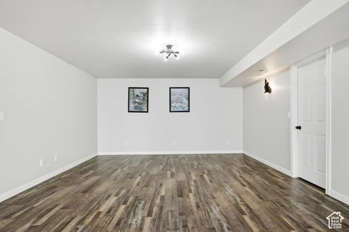 Spacious room featuring wood-finish flooring, white baseboards, and neutral wall tones