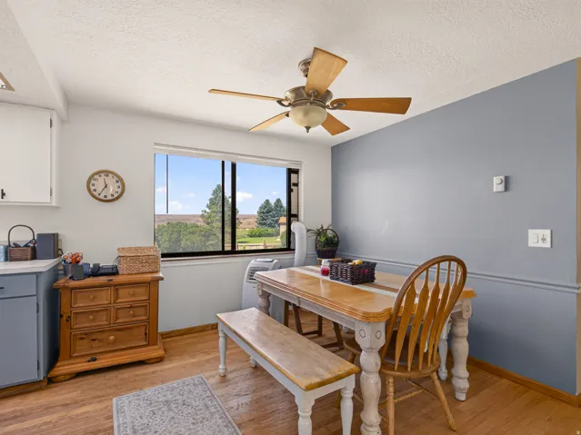 Dining area featuring wood-finish flooring, a ceiling fan with light fixture, and a window with outdoor scenery