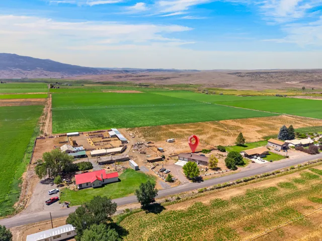 Expansive property featuring a collection of outbuildings, substantial agricultural fields, mountain backdrop, and established trees