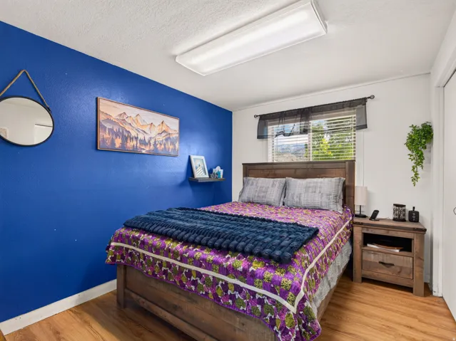 Spacious room featuring wood-finish flooring, a window with horizontal blinds, and a built-in closet