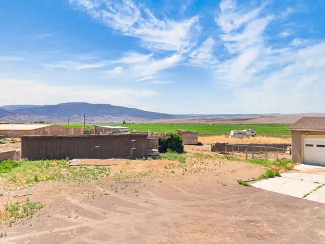 Expansive agricultural land featuring a large shed, a detached garage, and distant mountain scenery