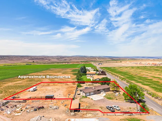 Aerial perspective showcasing the property's approximate boundaries, a single-story residence with an attached two-car garage, and a spacious undeveloped lot