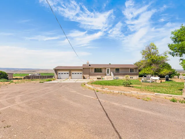 Ranch-style exterior with a two-car garage, a covered front entry, and a gravel driveway
