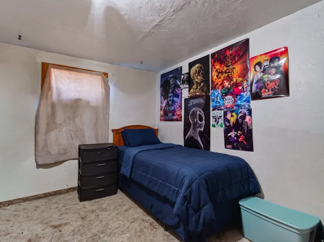 Bedroom featuring light-colored walls and a textured ceiling