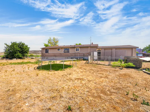 Expansive outdoor area with a tan-colored residential structure, fenced sections, and surrounding vegetation
