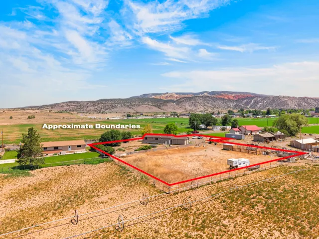 Expansive rural property featuring a single-story residence, multiple outbuildings, and a large open field