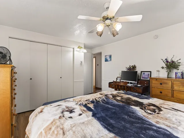 Bedroom featuring wood-finish flooring, a ceiling fan with integrated lighting, and multiple white bi-fold closets