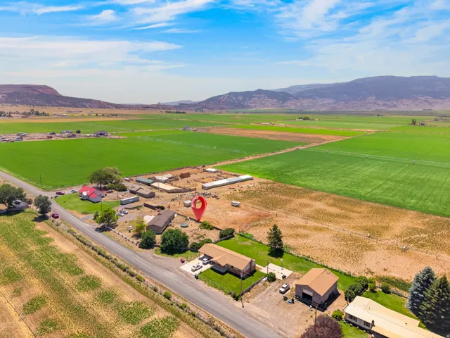 Expansive rural property featuring a primary residence, a large outbuilding with a brown roof, and significant surrounding land