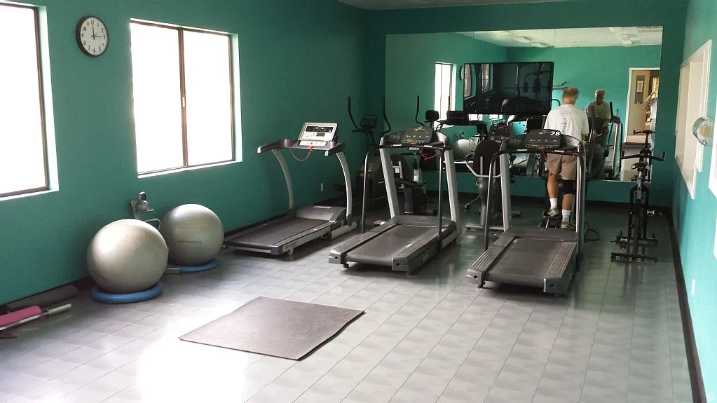 Dedicated fitness room featuring a full-wall mirror, two windows, and light-toned tile flooring