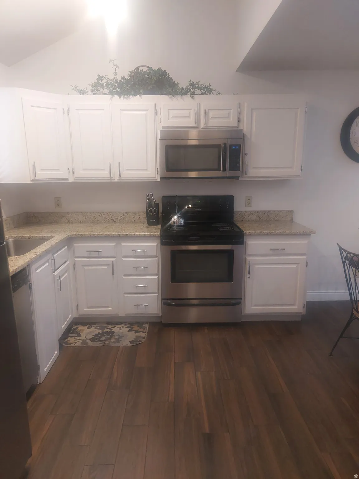 Kitchen featuring white cabinetry, stainless steel range, stainless steel microwave, and wood-finish flooring