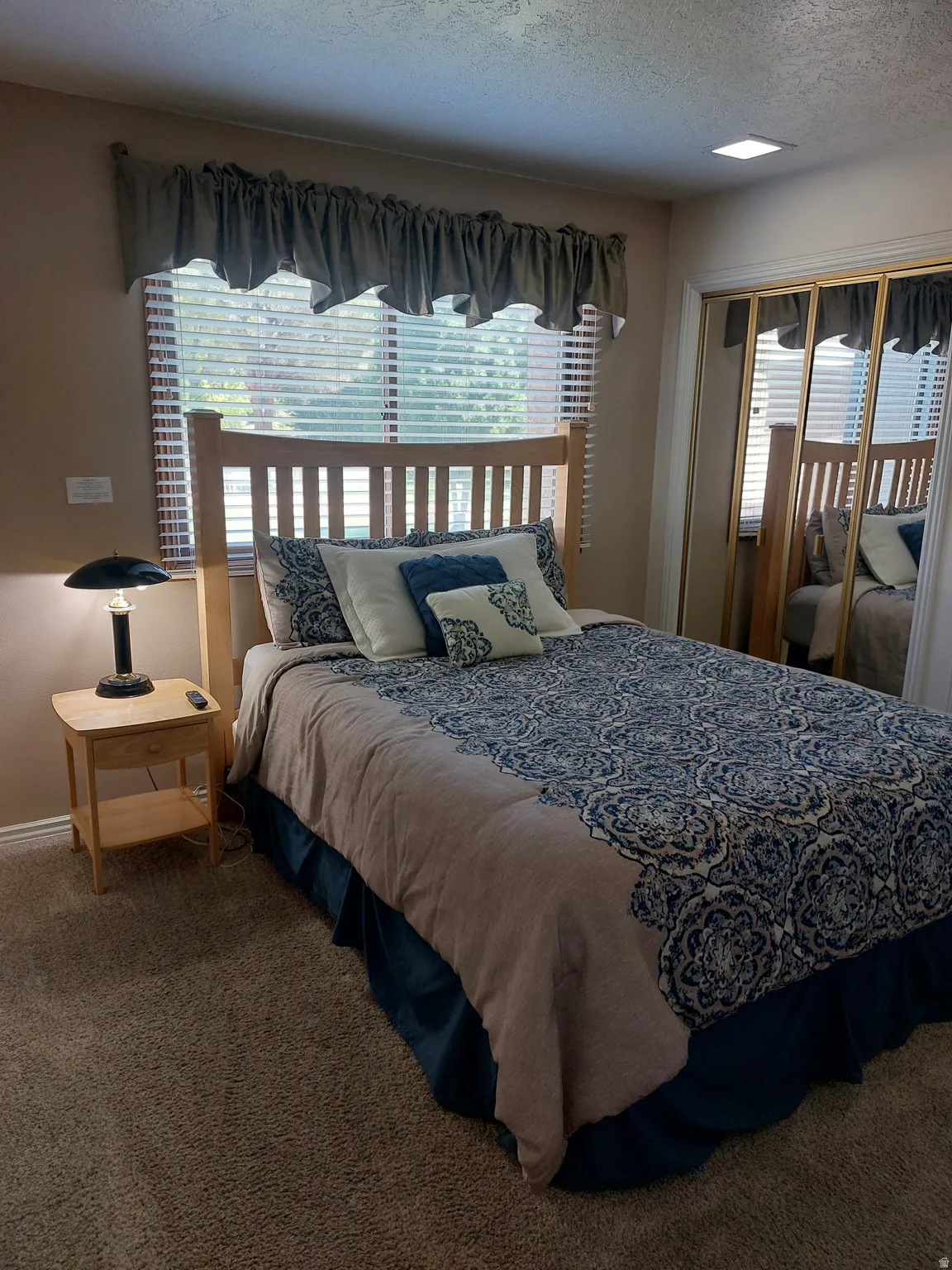 Carpeted room featuring a window with blinds, a built-in mirrored closet, and an overhead square recessed light fixture and 1/2 bath