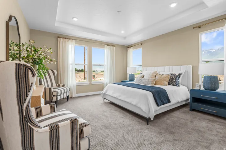 Spacious bedroom featuring multiple windows, a tray ceiling, recessed lighting, and neutral-toned wall paint
