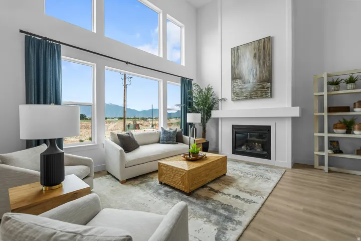Living area featuring high ceilings with upper transom windows, a floor-to-ceiling fireplace with a mantel, and wide plank wood-finish flooring