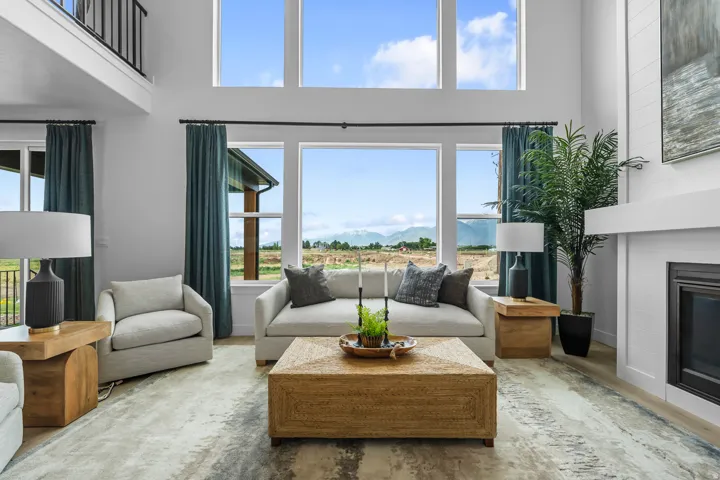 Two-story living area featuring extensive window-lines, a built-in fireplace with white mantel, a second-story interior balcony, and light-tone flooring