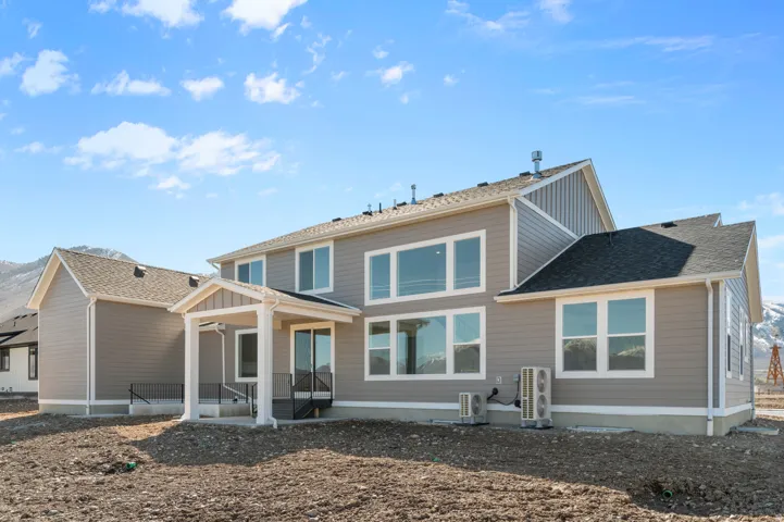 Two-story property featuring light grey siding, white trim, and a dark shingle roof