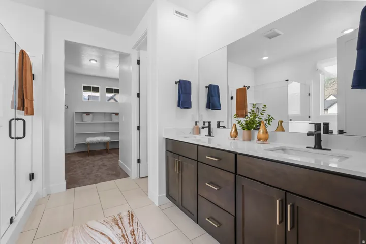 Dual vanity with dark wood-finish cabinetry, white countertops, and matte black fixtures
