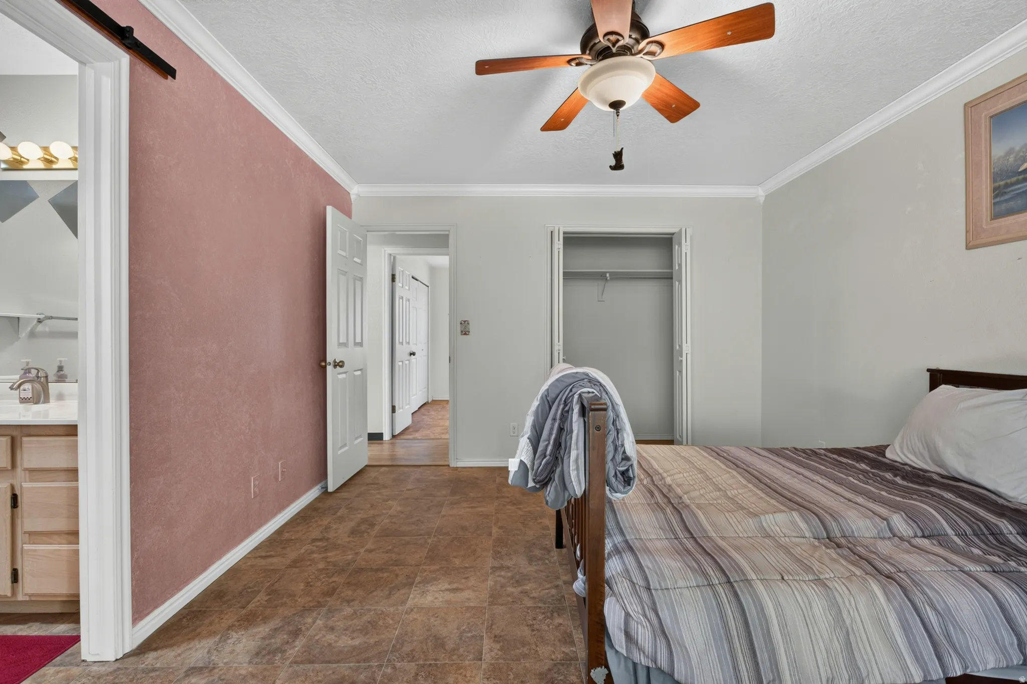 Room featuring crown molding, two panel doors, a built-in closet with bi-fold doors, and a ceiling fan with light fixture