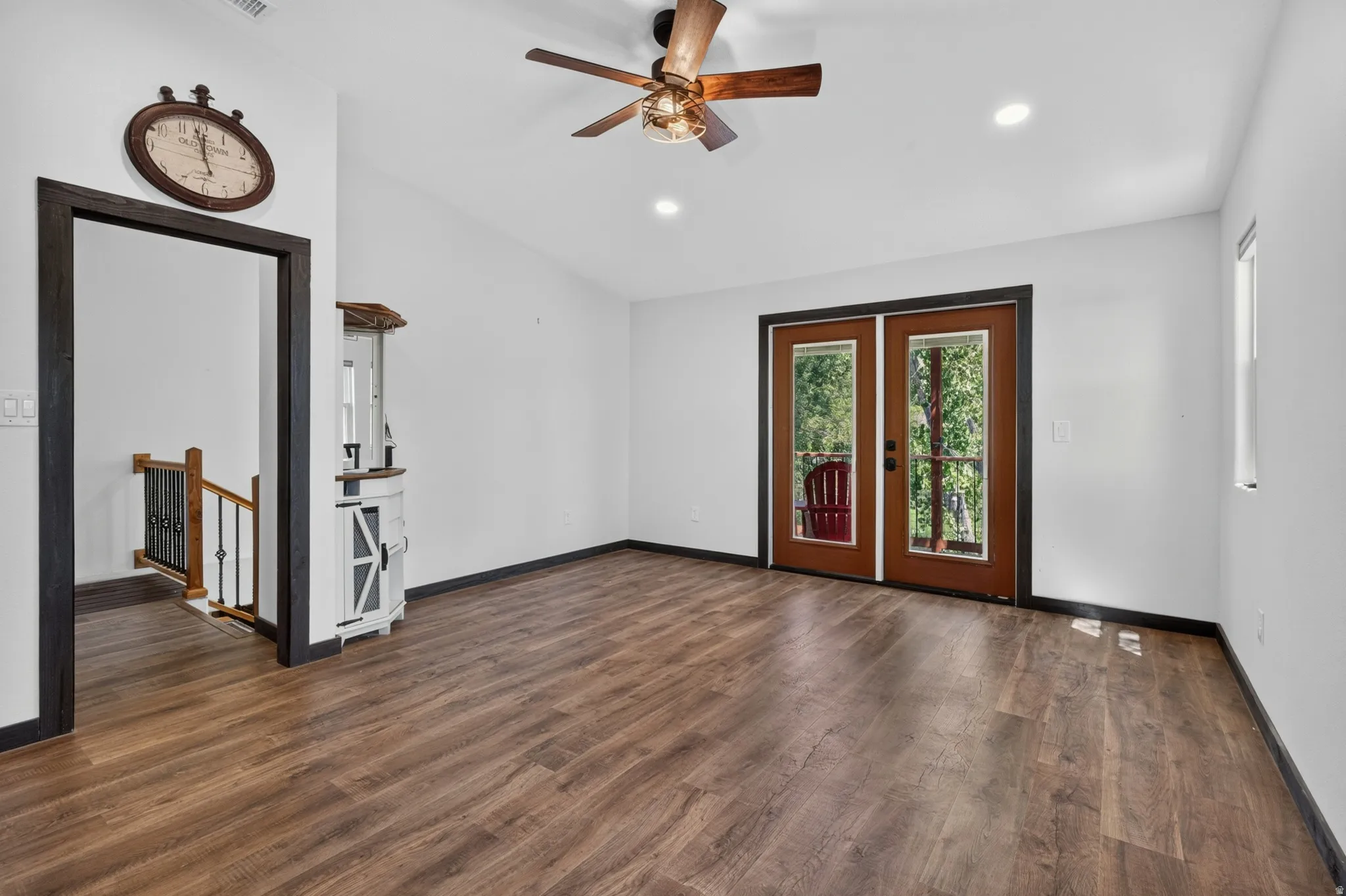 Spacious interior featuring wood-finish flooring, white walls, and a ceiling fan