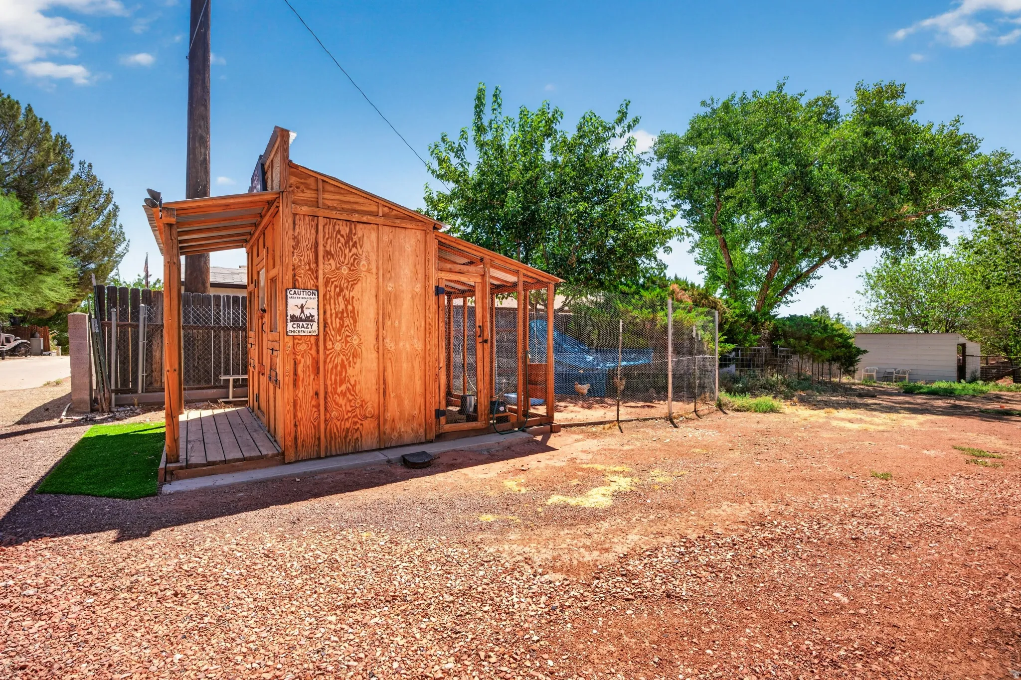 Freestanding wood-paneled structure with a covered porch area and an attached fenced enclosure
