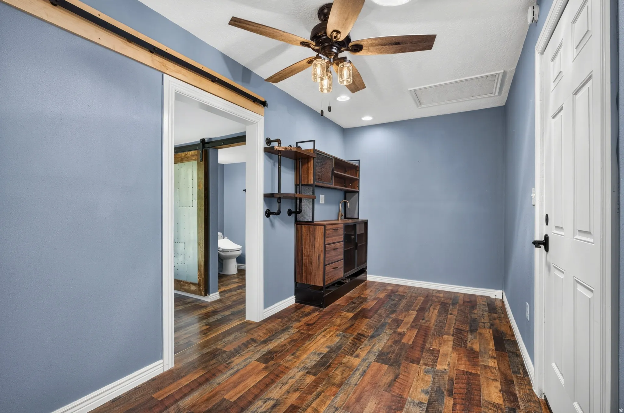 Wood-finish flooring throughout, featuring a built-in wet bar with industrial-style shelving and a modern faucet