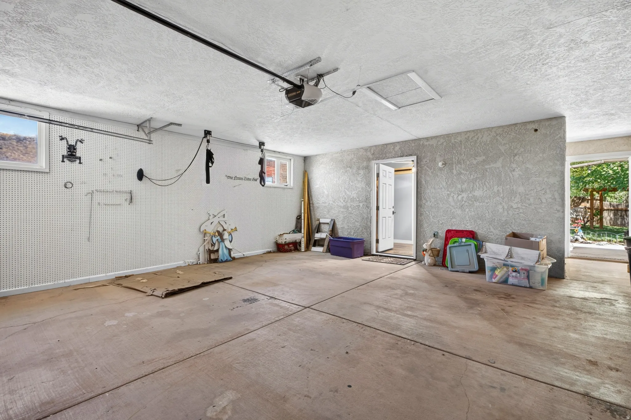 Spacious garage with concrete flooring, automatic garage door opener, and multiple windows providing natural light