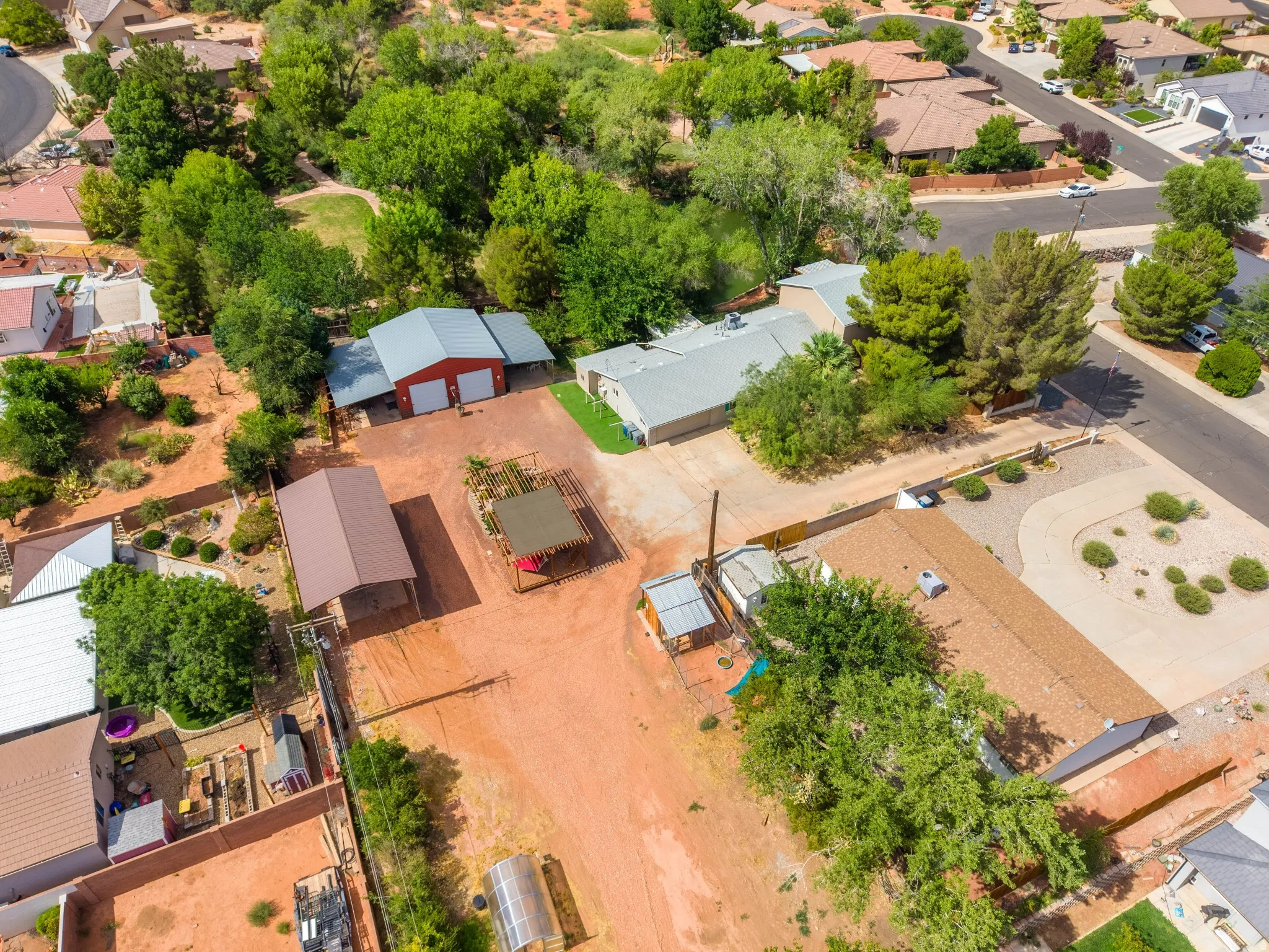 Expansive property featuring multiple outbuildings, including a red barn with white garage doors and a large metal carport