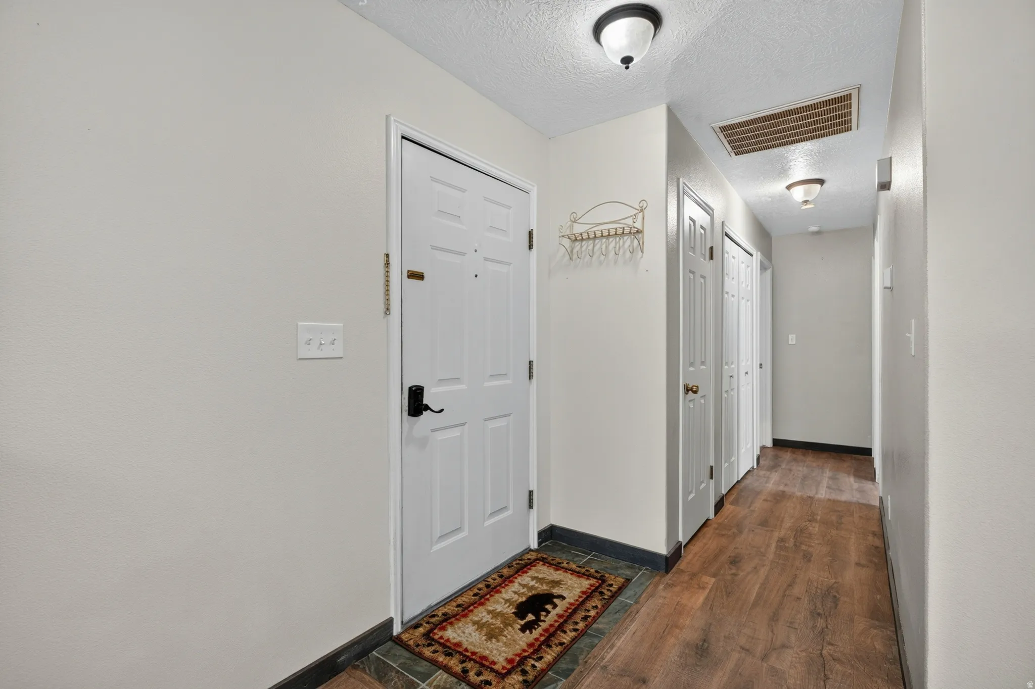 Entryway with a white door, slate tile flooring, and wood-finish flooring