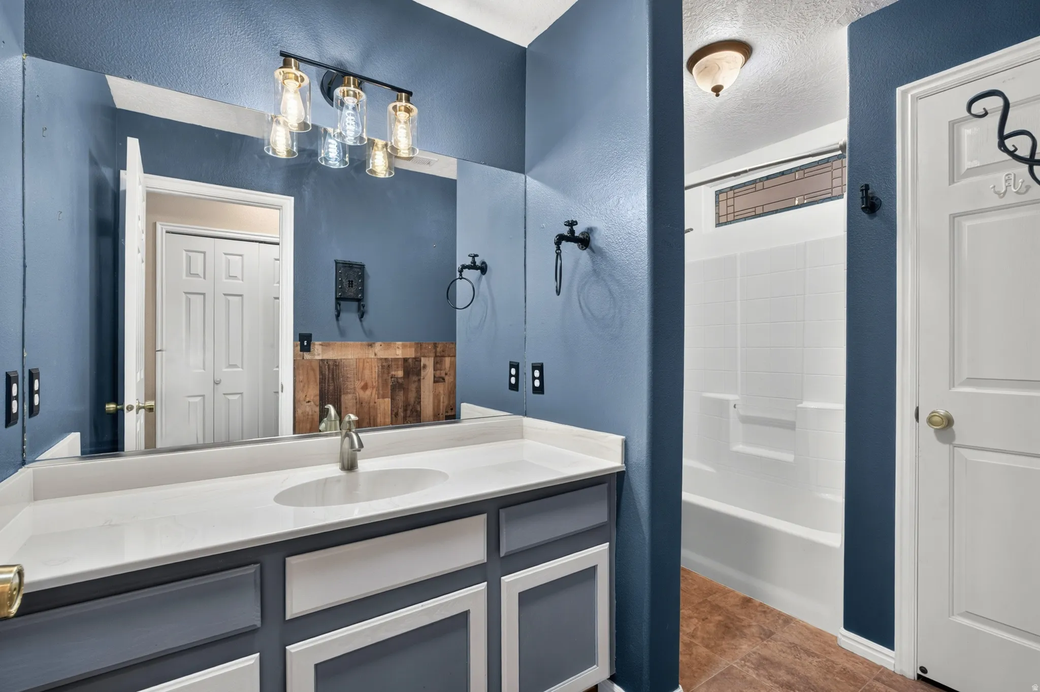 Bathroom vanity featuring a single basin sink, light-toned countertop, and dark cabinetry with white trim