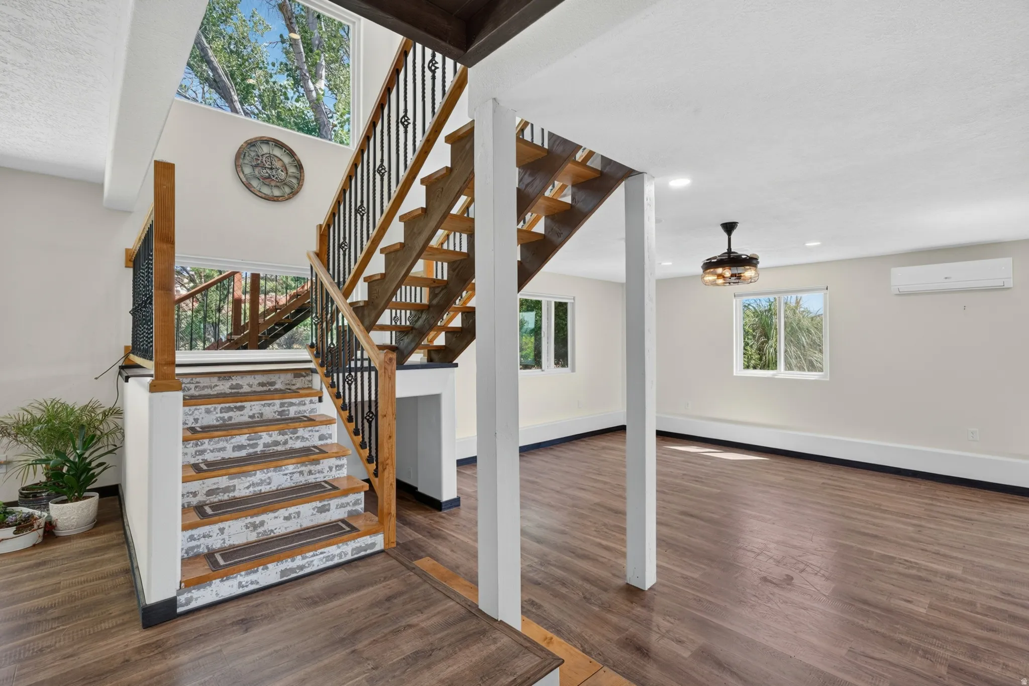 Two-story staircase with wood treads and black wrought iron balusters