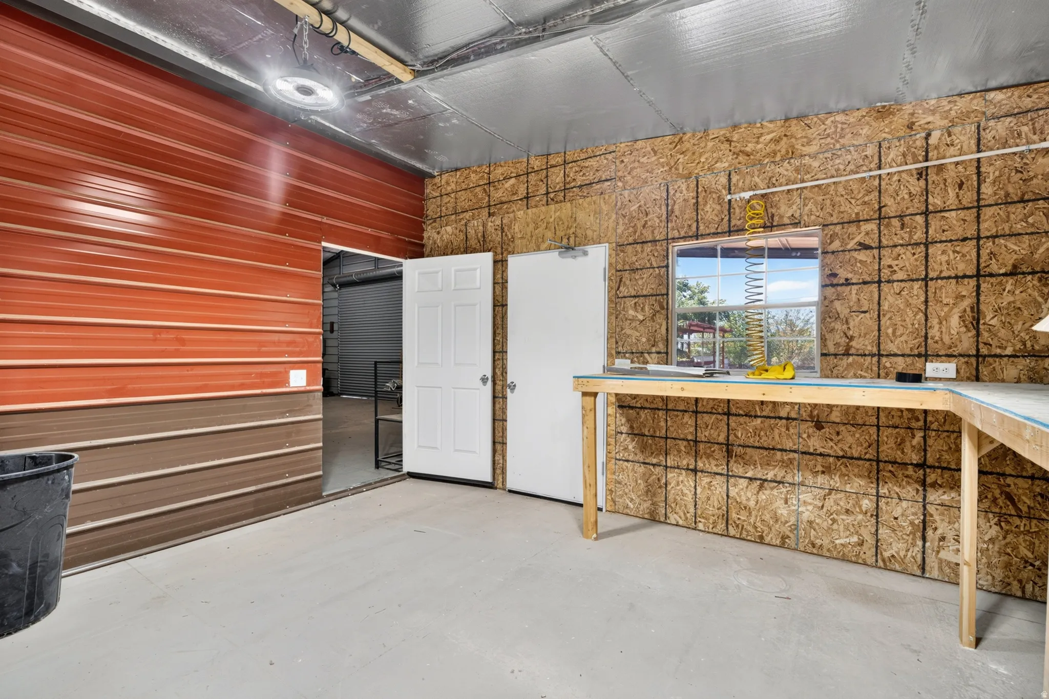 Workshop space featuring a built-in workbench, a window, concrete flooring, and multiple entry points