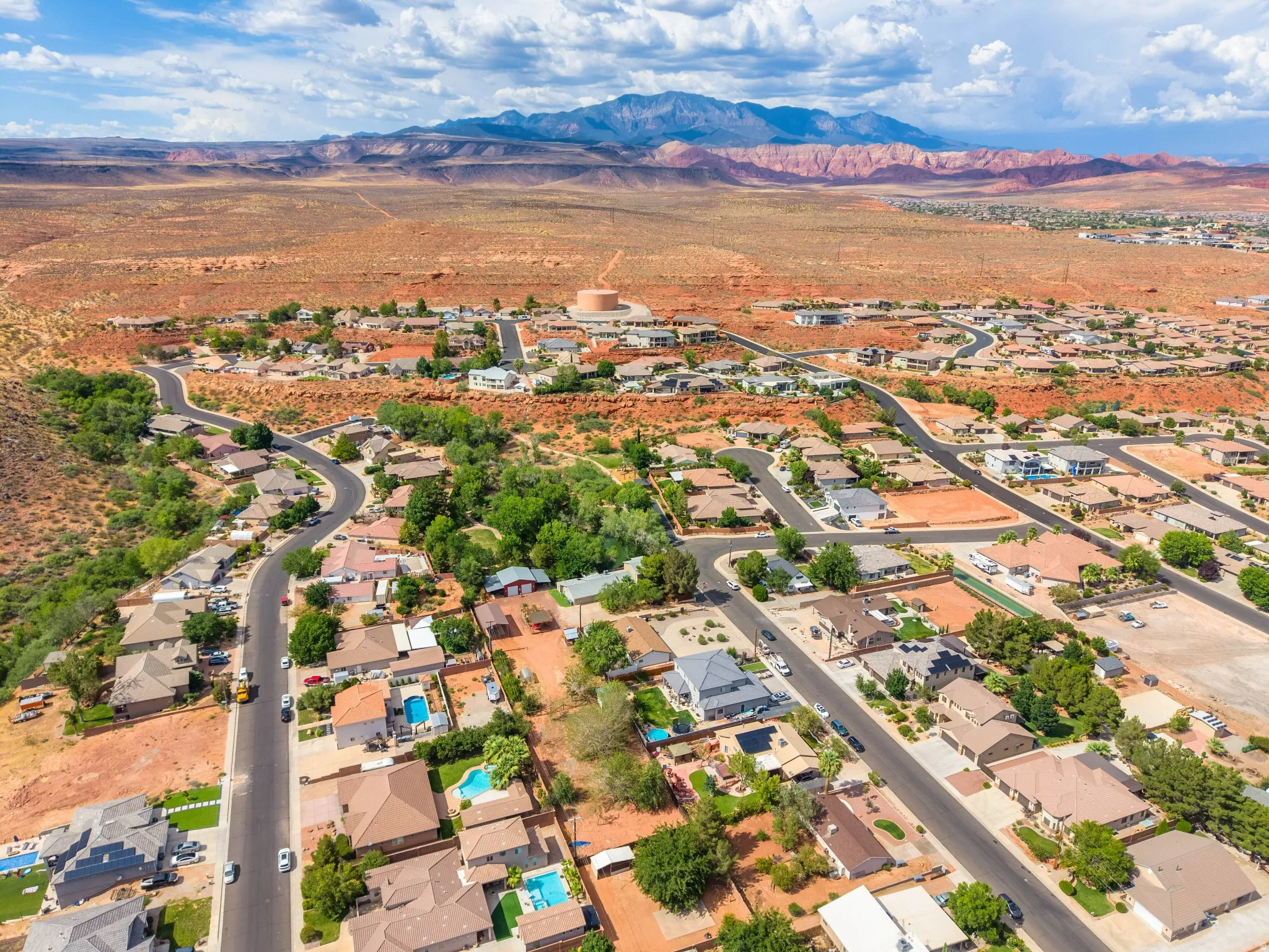 Expansive residential landscape featuring a variety of housing styles, established streets, and mature green spaces, set against a distant mountain range