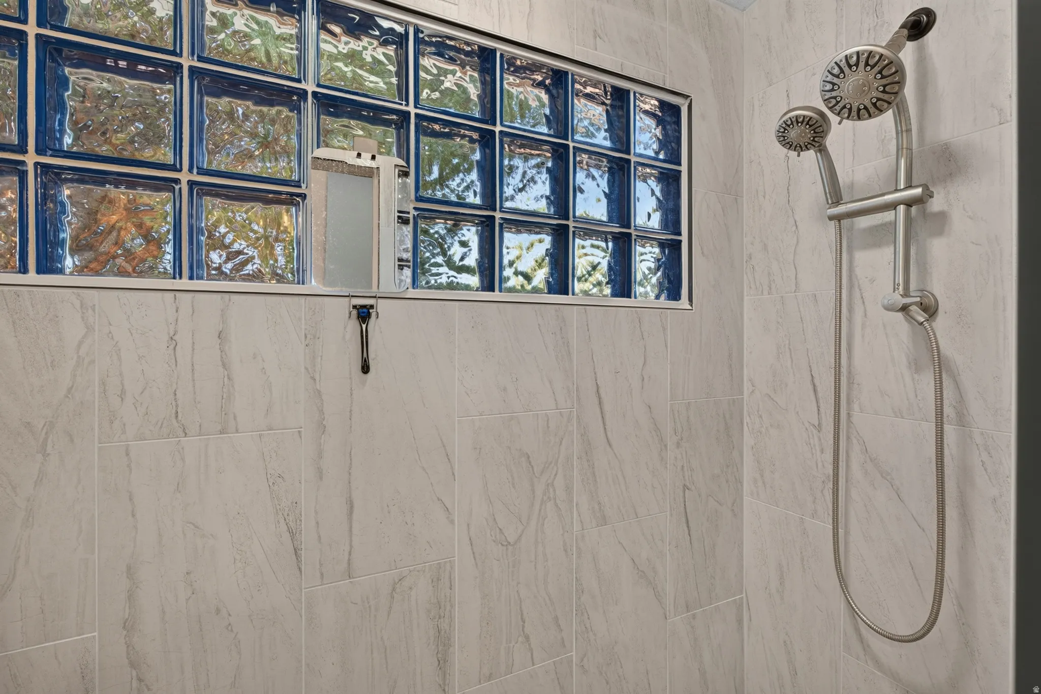 Shower featuring light-toned tilework and a glass block window
