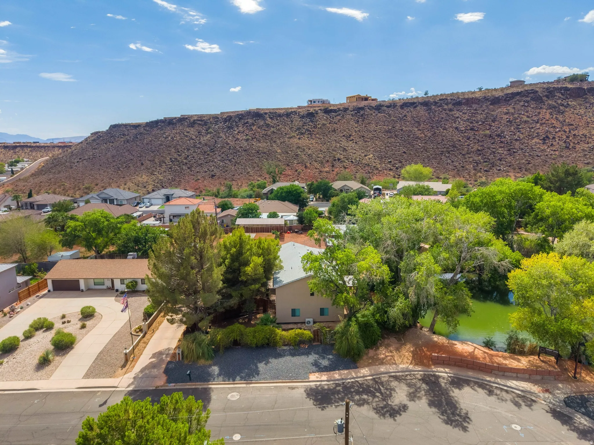 Aerial perspective featuring a residential street with properties set against a prominent red rock hillside