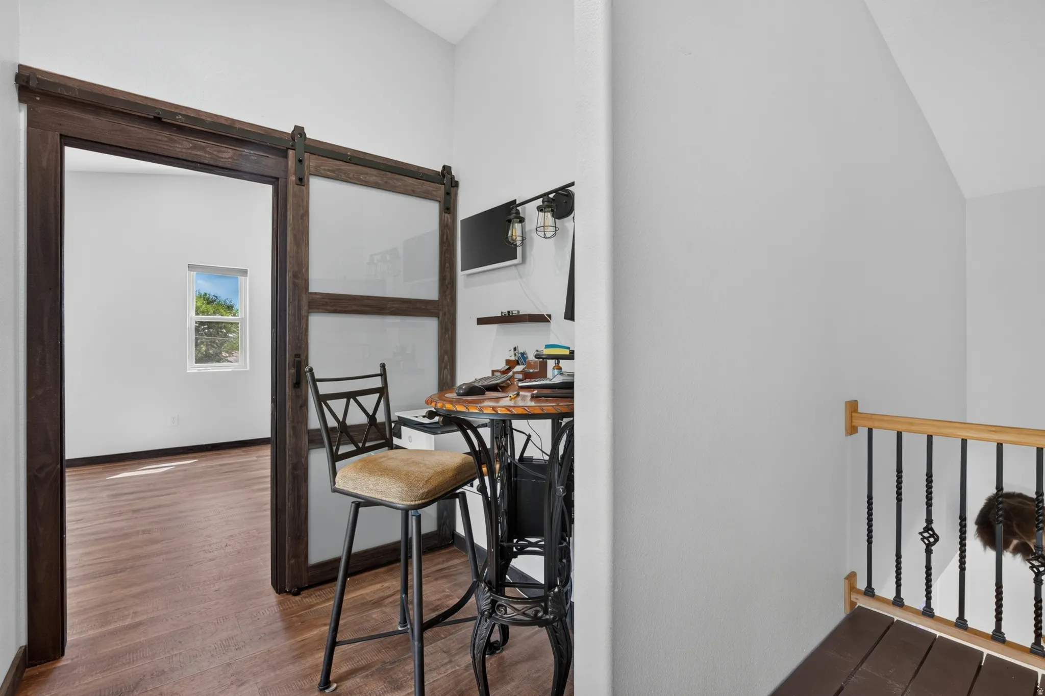 Wood-finish flooring throughout, featuring a dark wood barn door with frosted glass panels