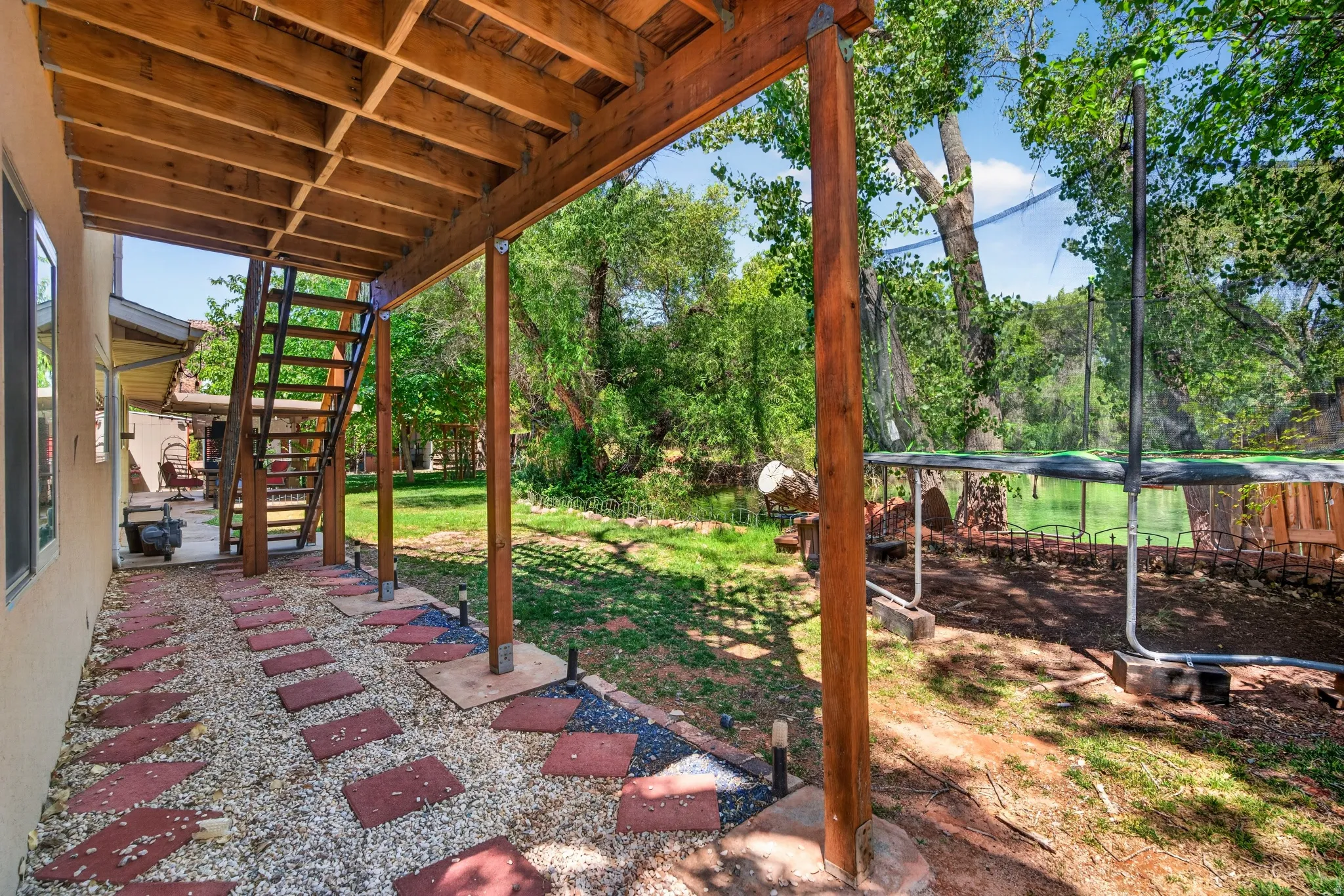 Covered outdoor patio area featuring a gravel and paver pathway