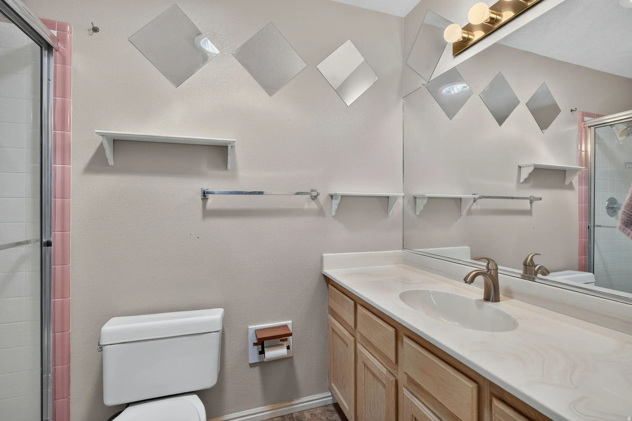 Bathroom vanity featuring a light-toned countertop, integrated sink, and brushed nickel faucet