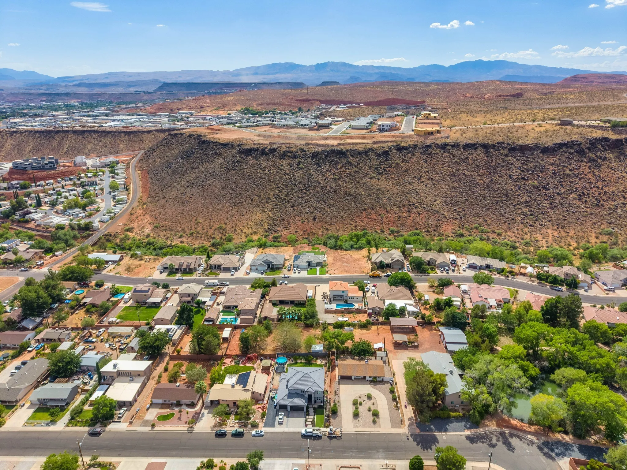 Residential community featuring a variety of single-family homes, mature landscaping, and an adjacent natural landform