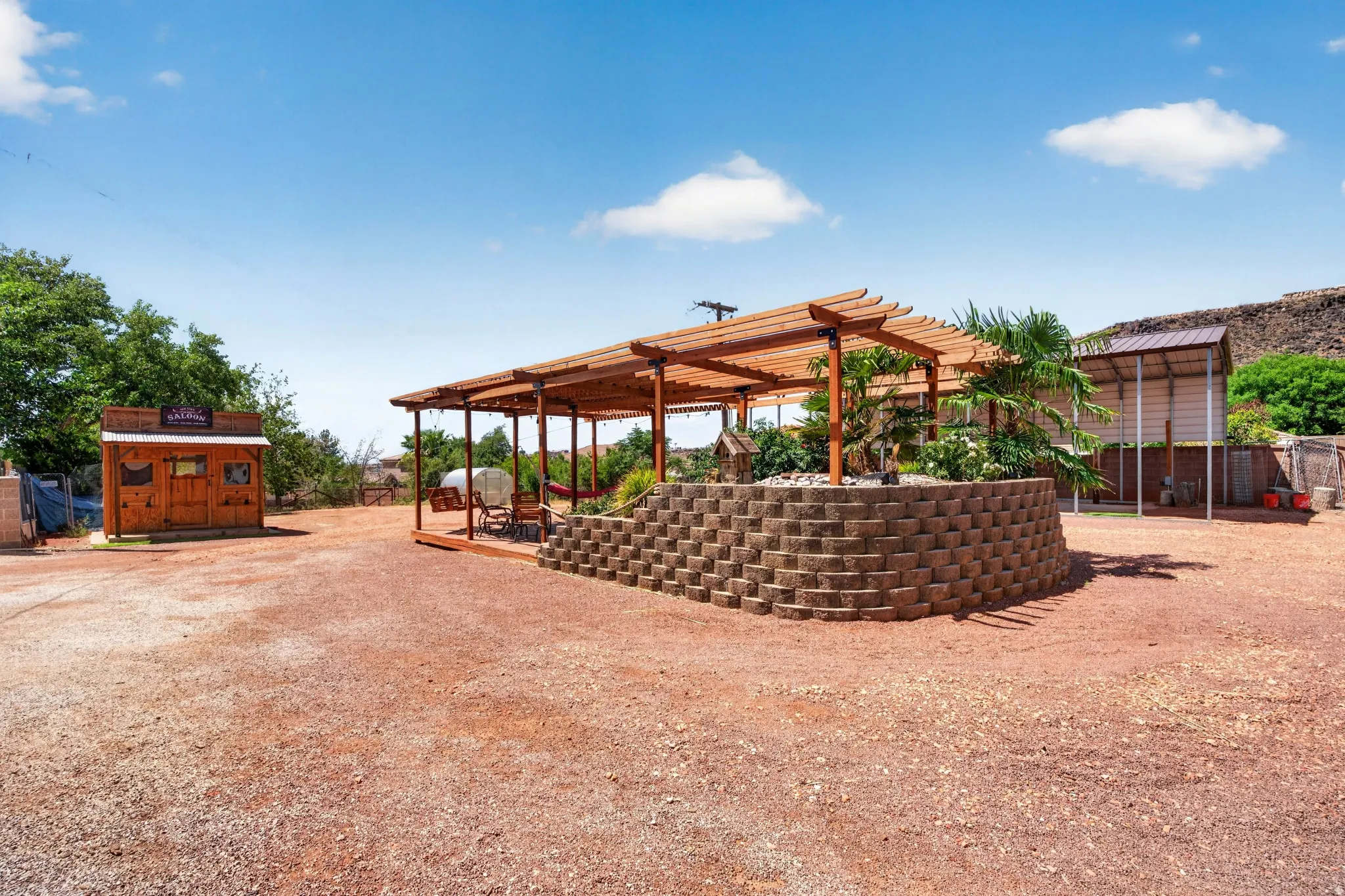 Expansive outdoor space featuring a wood pergola atop a stone-block raised planter, providing a shaded seating area
