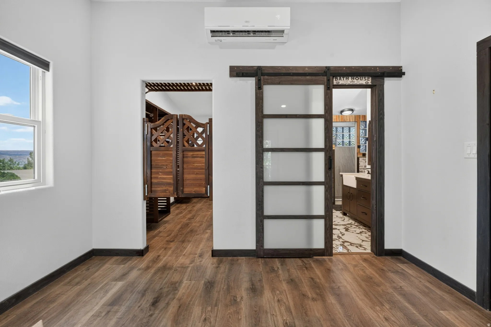 Wood-finish flooring throughout, featuring a white wall palette and dark trim