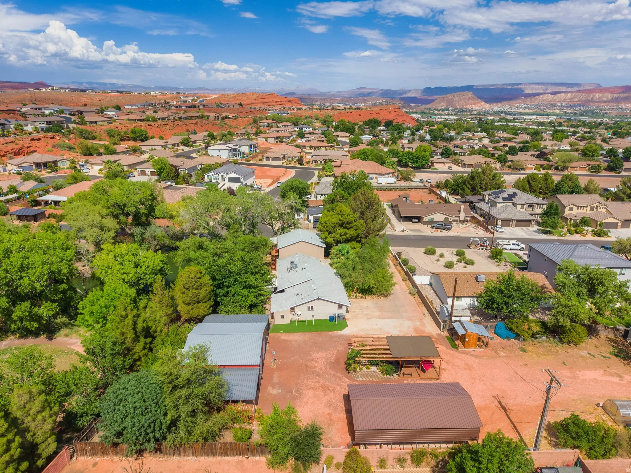 Aerial perspective showcasing the property's expansive lot, surrounded by abundant mature trees and natural desert landscaping